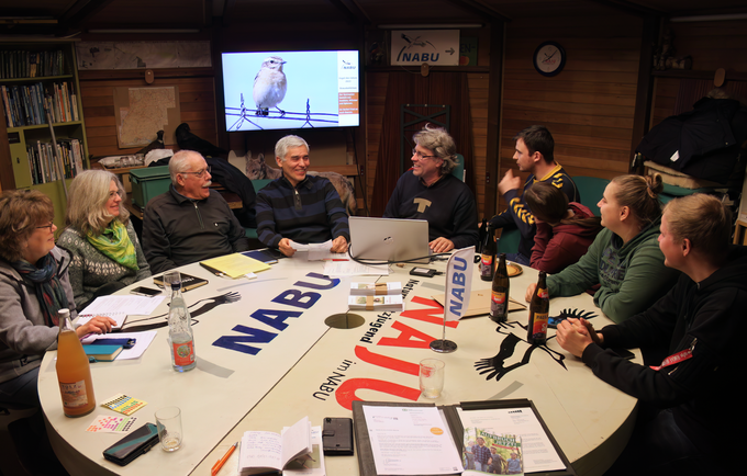 Mitarbeitertreffen im NABU Turm. Die Mitarbeiter sitzen um einen runden Tisch und diskutieren.